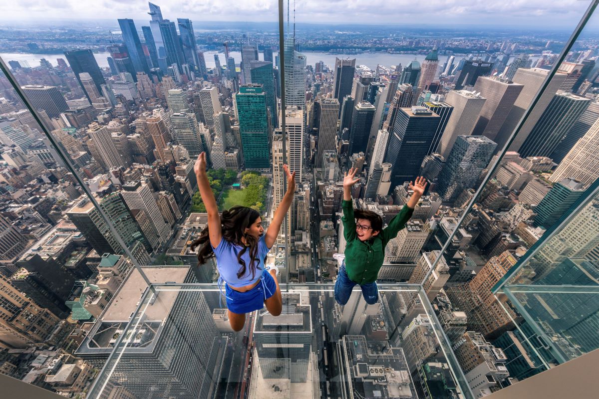 Two young kids jumping up with the NYC skyline in the background