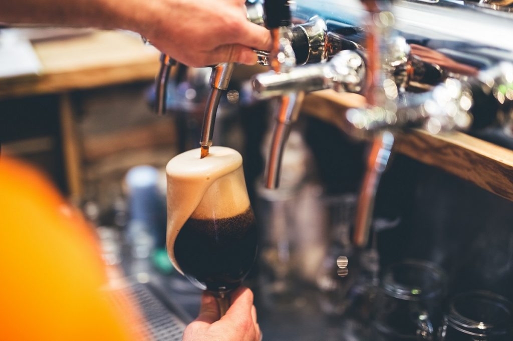 Bartender pours a beer at a tap