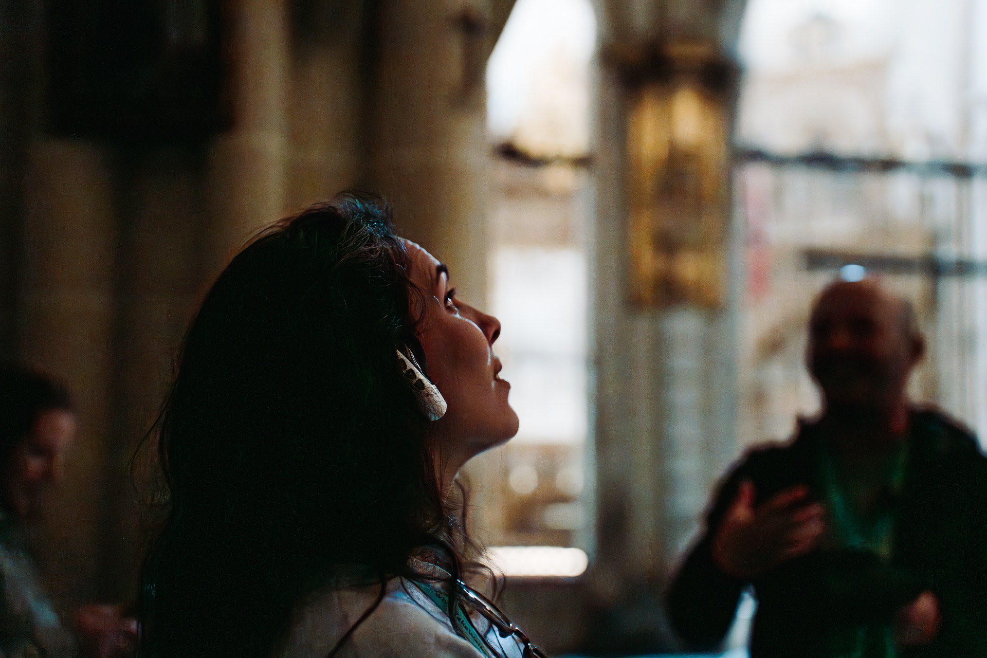 Tour guest listens to tour guide via her headphone ear piece as she stares up at a historic site