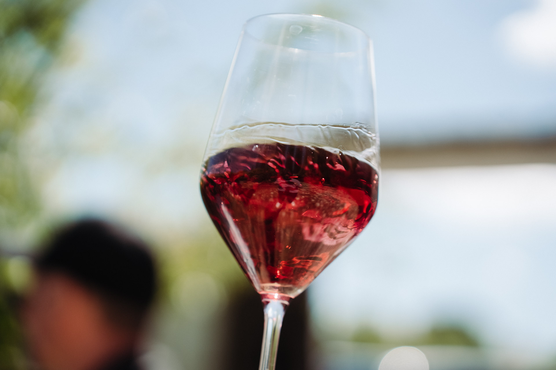 Swirling a glass of red wine so that the light is reflected off of the drink