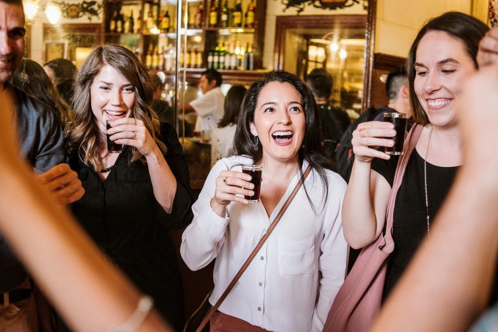 Group of friends sipping small glasses of Spanish vermouth inside of a 100-year-old Madrid bar (Casa Labra).