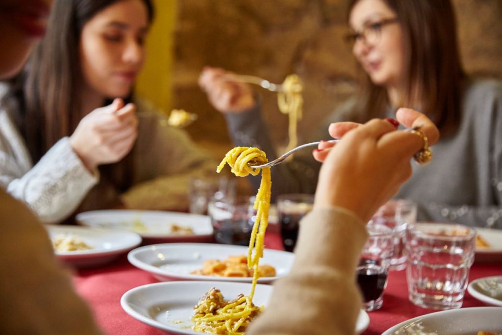 people eating plates of pasta and drinking wine