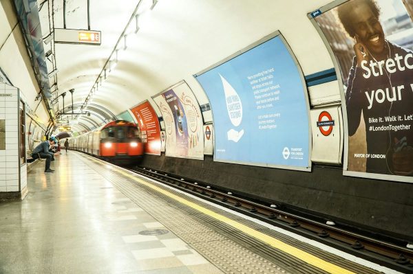 An oncoming train approaches in London while passengers wait to board the train.