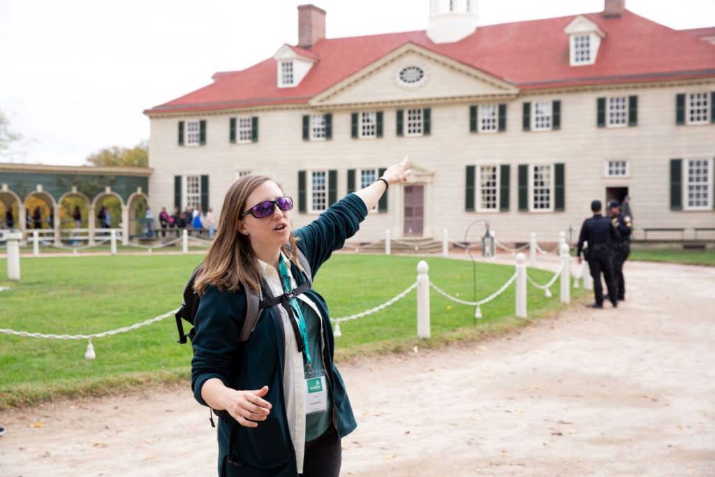 woman pointing to a historic house