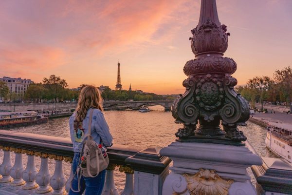 woman standing on a bridge watching the sunset in Paris.