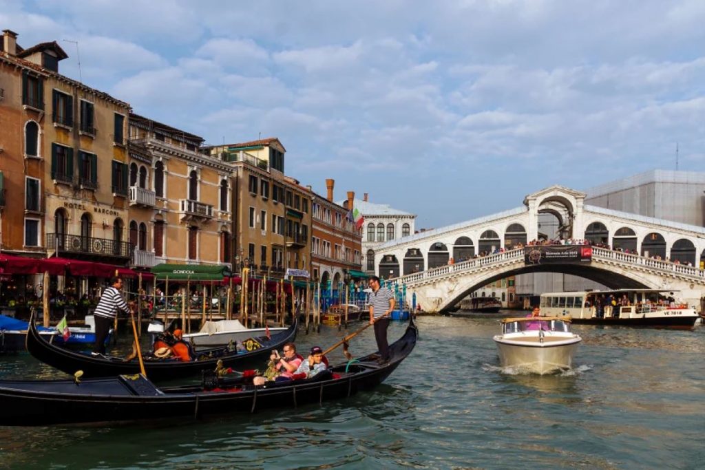 People riding in a gondola towards a bridge