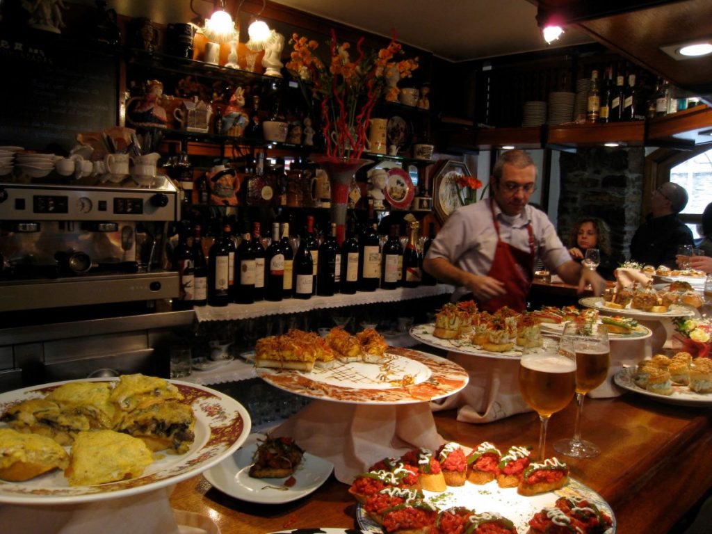 A bartender working behind a counter full of pintxos in San Sebastian, Spain. 