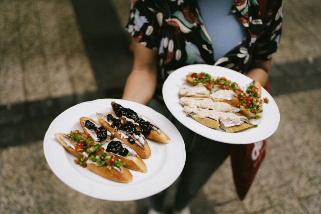 A woman holding two plates full of pintxos in San Sebastian, Spain.