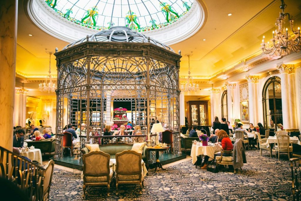 People sitting at a 5-star hotel drinking afternoon tea in London. 