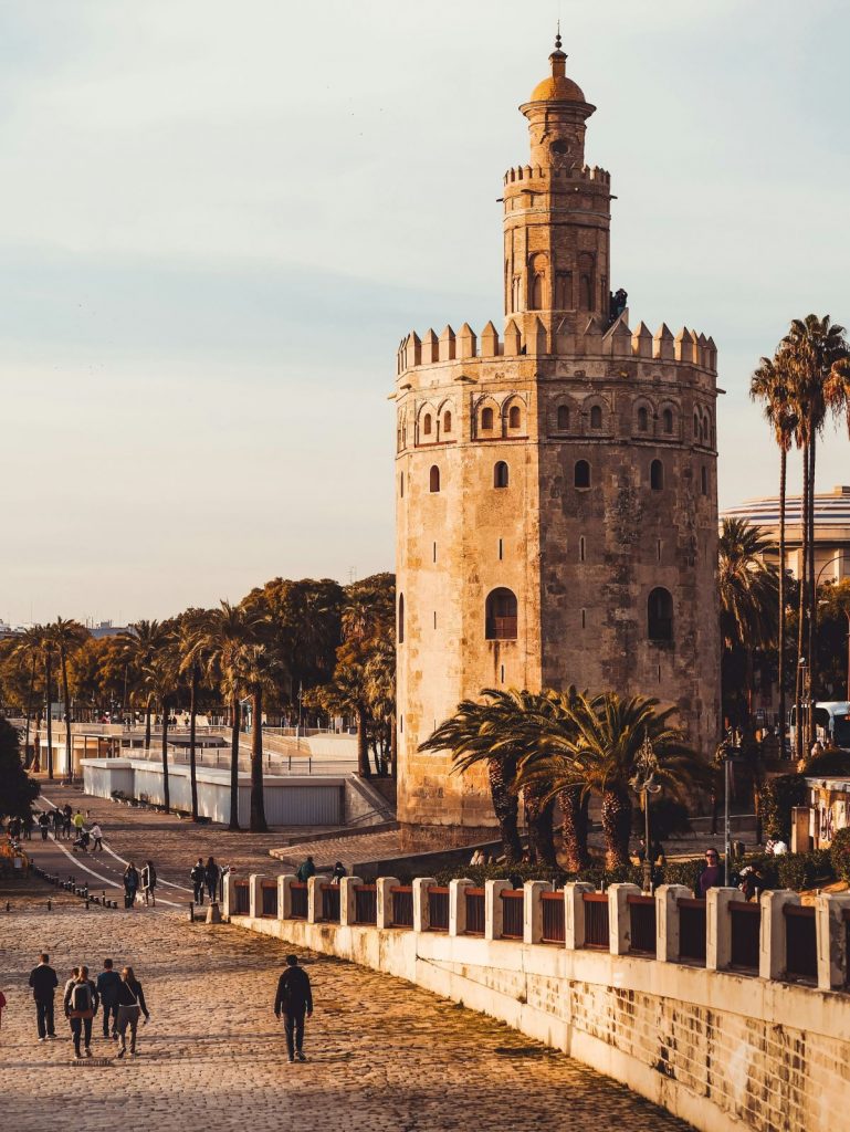 People walking and cycling near Torre del Oro in Seville. 