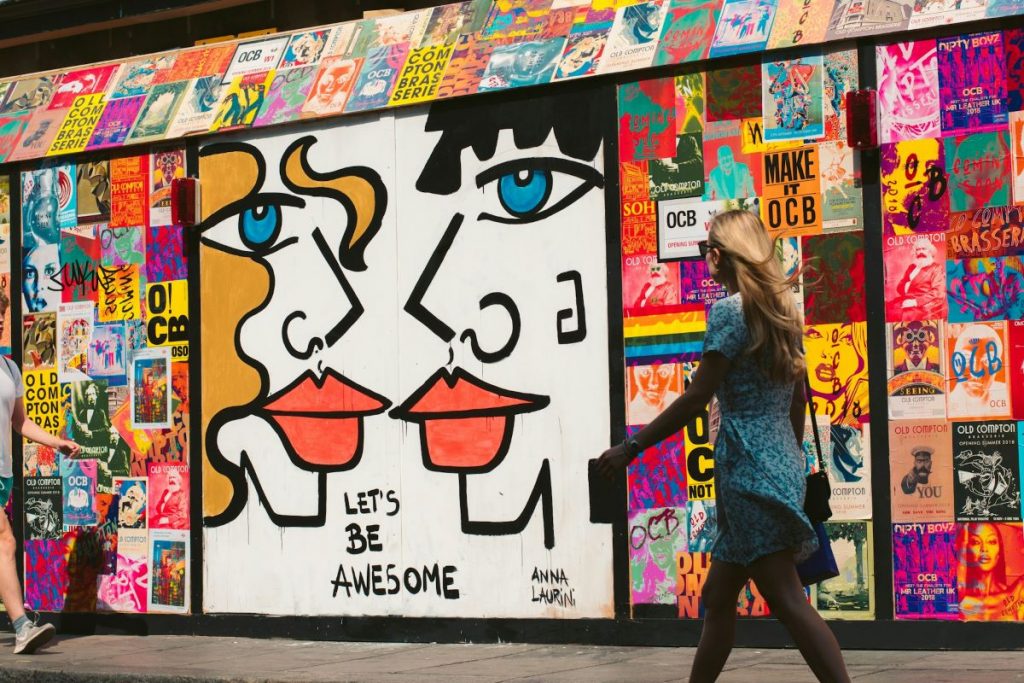 A woman walking by a colorful wall with graffiti and fliers in SoHo.