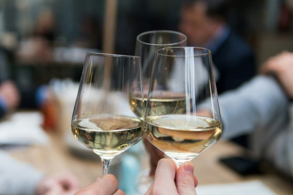 People clinking wine glasses filled with white wine from San Sebastian. 