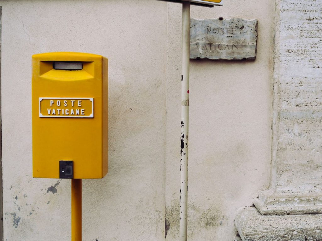 Yellow post box against beige wall