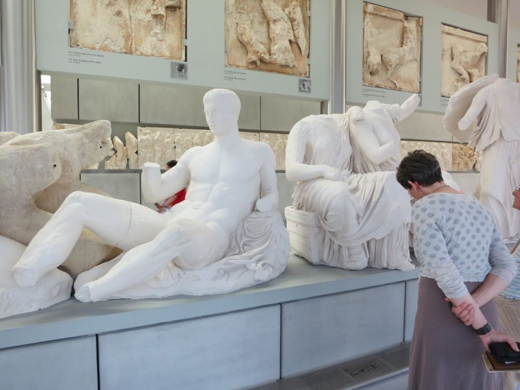 A woman looking at the pediment sculptures in Athens. 