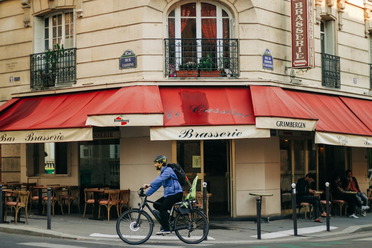 Person riding a bike in front of a restaurant in Paris