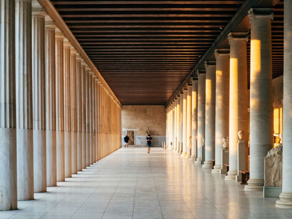 A man walks down a corridor of a museum. 