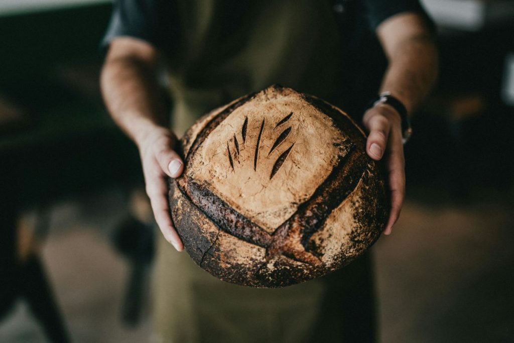 A man holding a baked loaf of bread. 