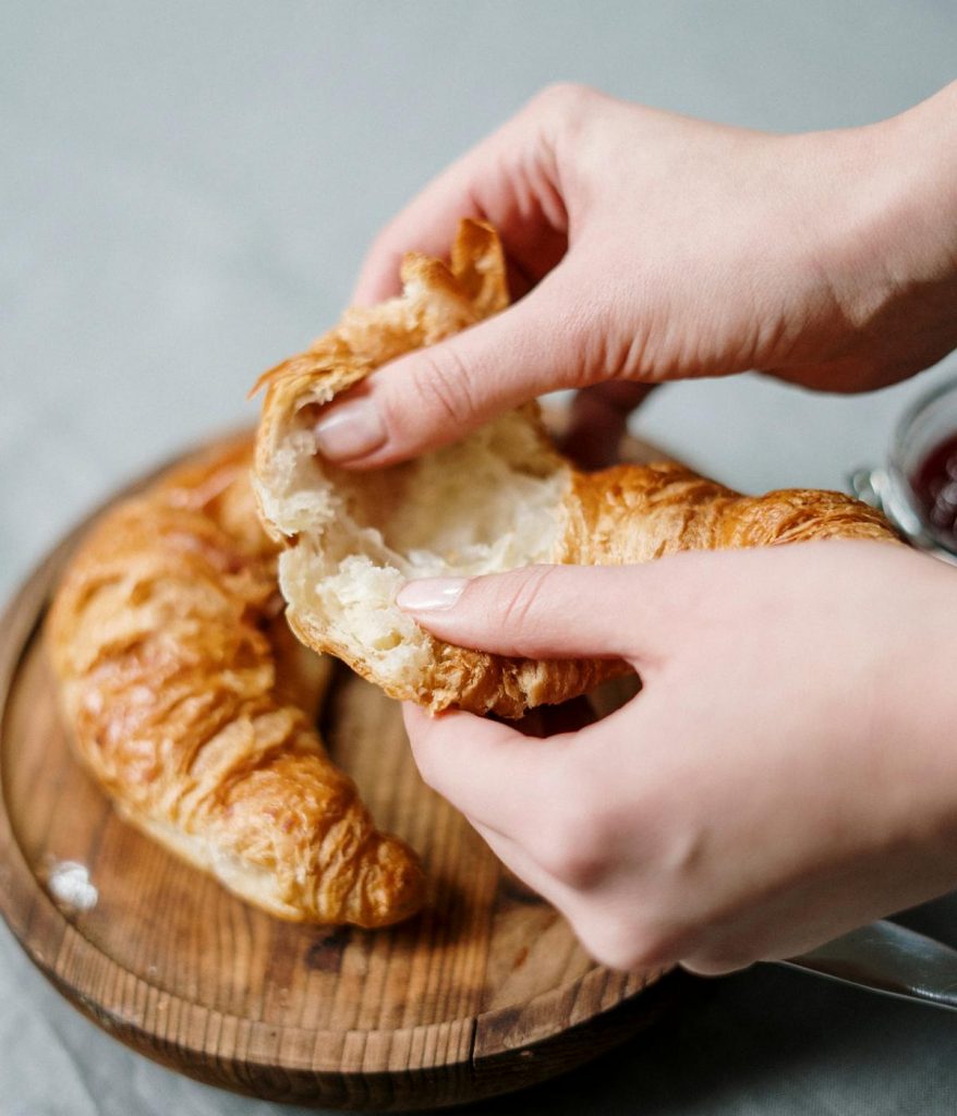 A person ripping open a croissant. 