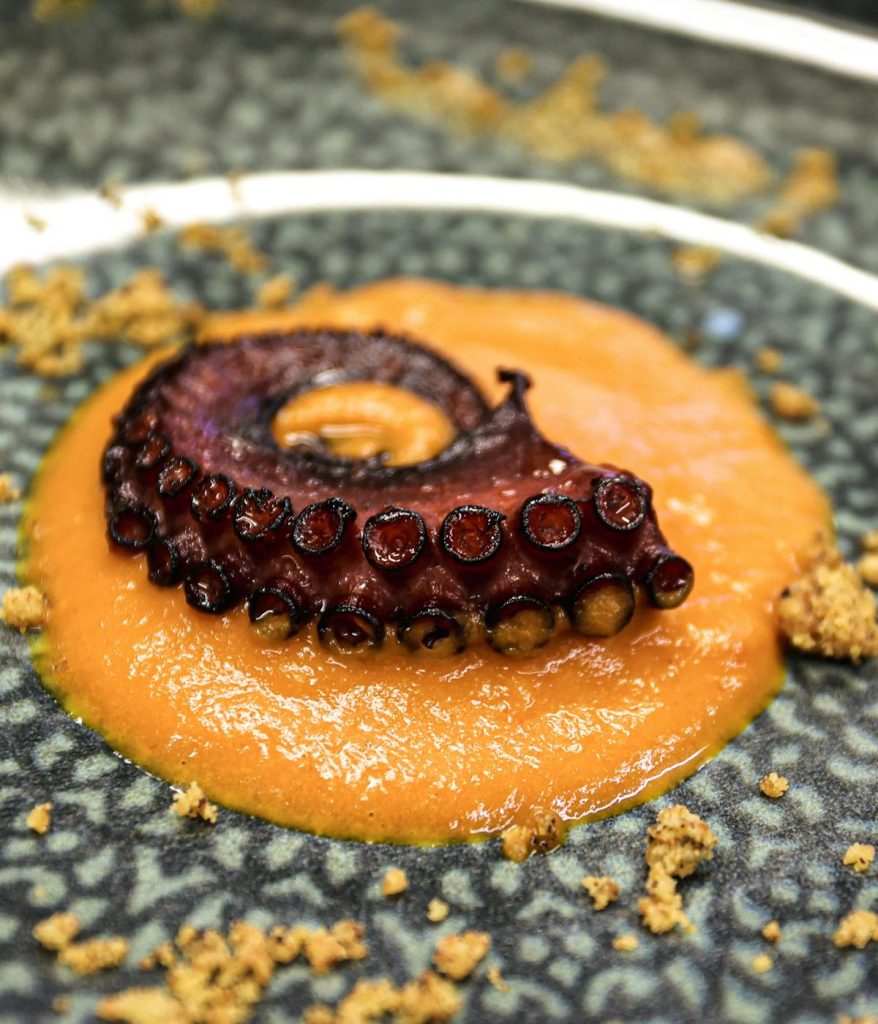 A close up of grilled octopus on top of a purée. 