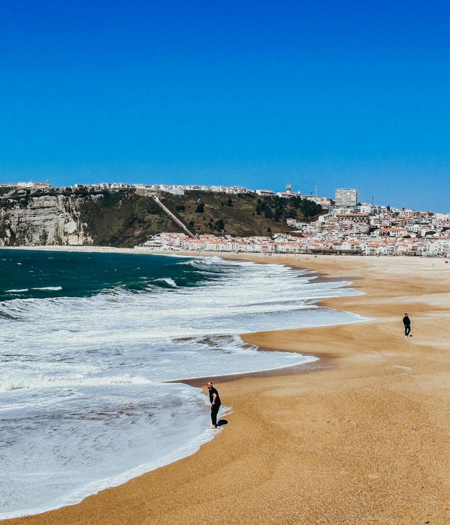 People walking on the beach in Nazaré, Portugal on one of their day trips from Lisbon. 