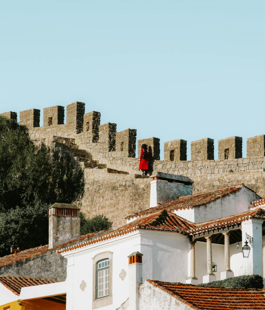 A woman climbing the Old City Walls of Obidos, Portugal on a day trip from Lisbon. 