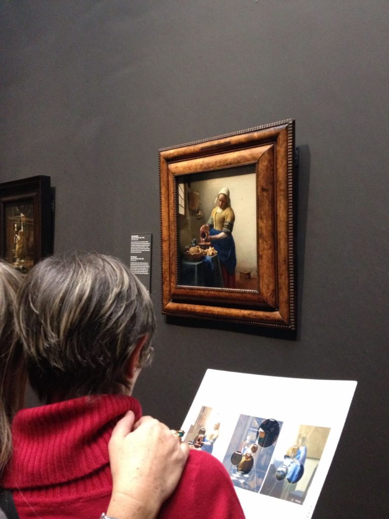 People looking at the Johannes Vermeer, Milkmaid painting. 