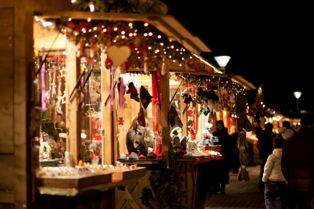 people wandering through christmas market stands