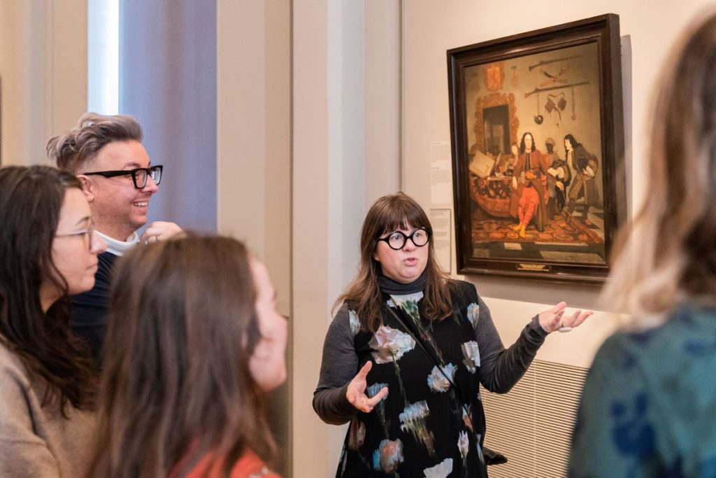 A tour guide explaining famous paintings to a group of people at the Rijksmuseum