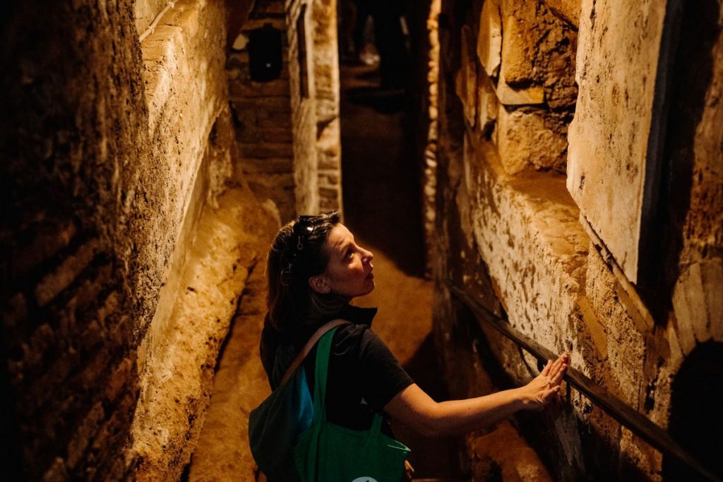 A woman walking down steps into the Catacombs in Rome. 