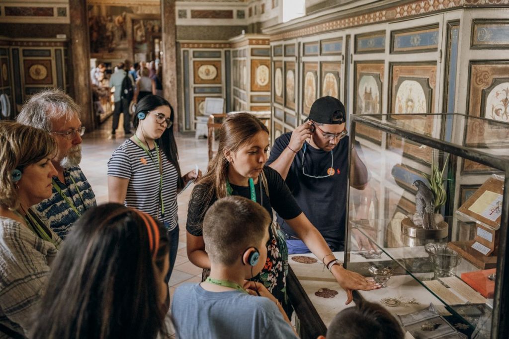 A Walks Tours guide talking about artifacts in a glass case to a group of visitors at the Vatican museum. 