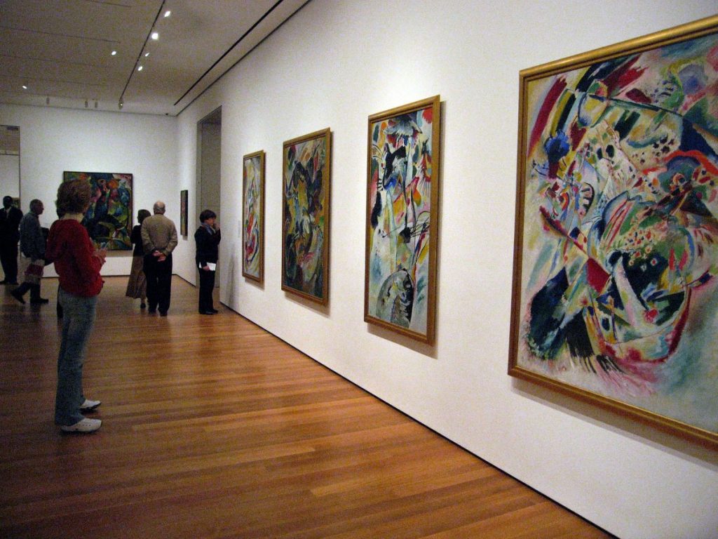 A group of people looking at a wall of Wassily Kandinsky's paintings. 