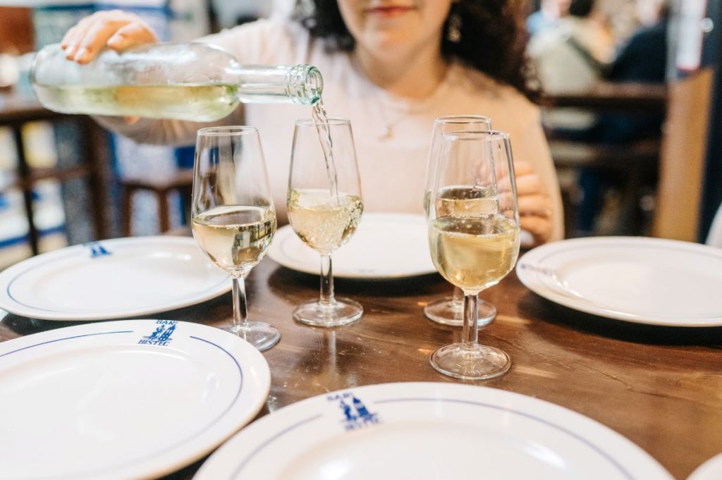 A woman pouring four glasses of Sherry wine at a restaurant in Jerez, Spain. 