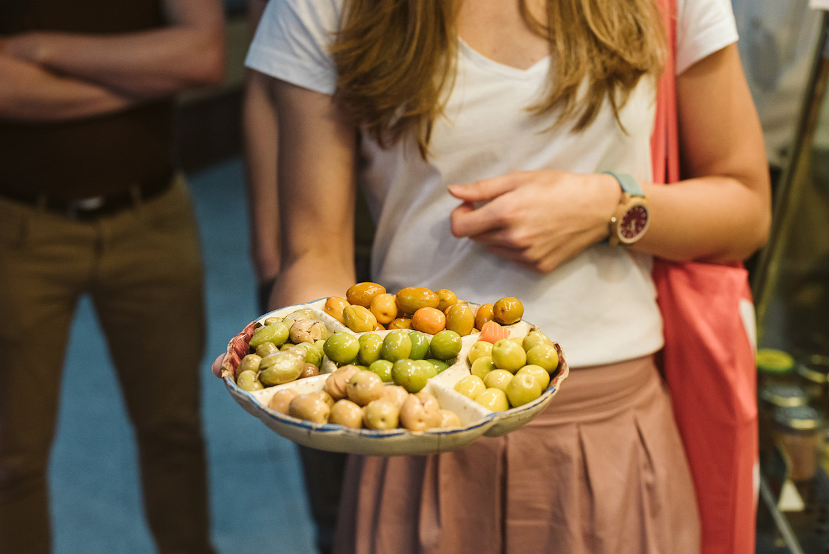 Person holding a plate of olives