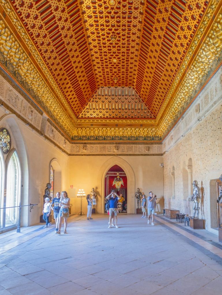 People walking around inside the Alcazar in Segovia, Spain taking pictures of the ornate ceiling. 