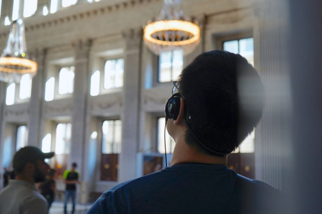 A man walking around different rooms of the H'ART museum in Amsterdam, listening to an audio tour. 