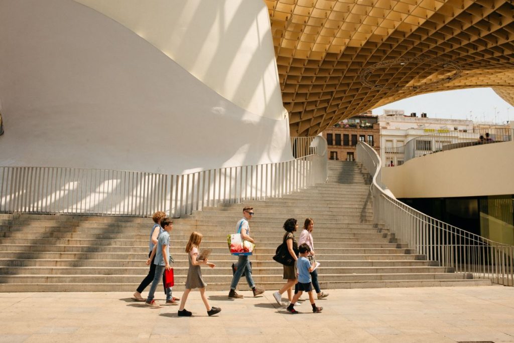 A group of adults and children walking under Las Setas in Seville. 