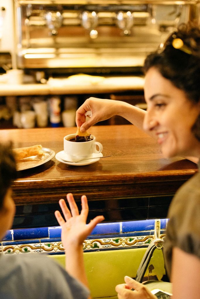 A woman and her child eating churros con chocolate. 