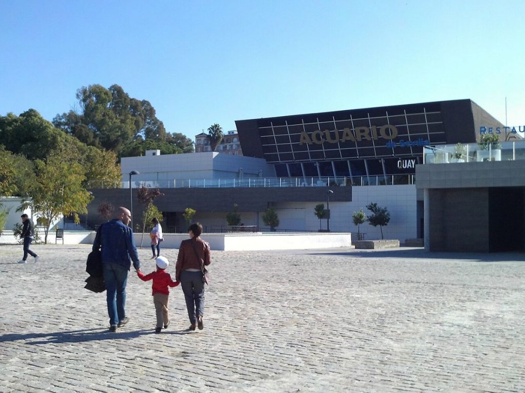 A family holding hands outside of the aquarium in Seville. 