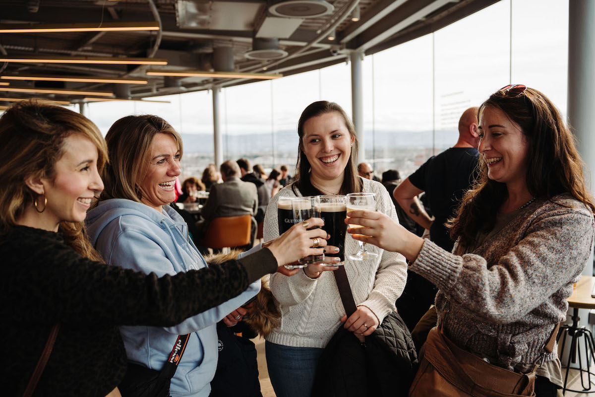 Group toasting with a pint of Guinness beer at a rooftop