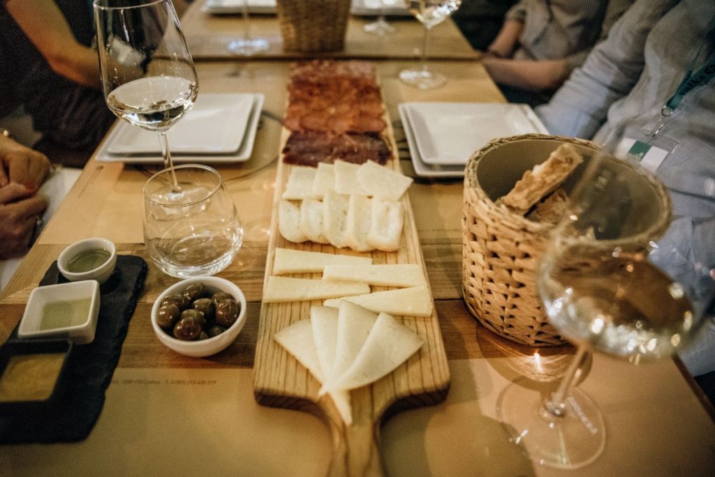 Portuguese wine, cheese, and sliced cured meats on a table. 