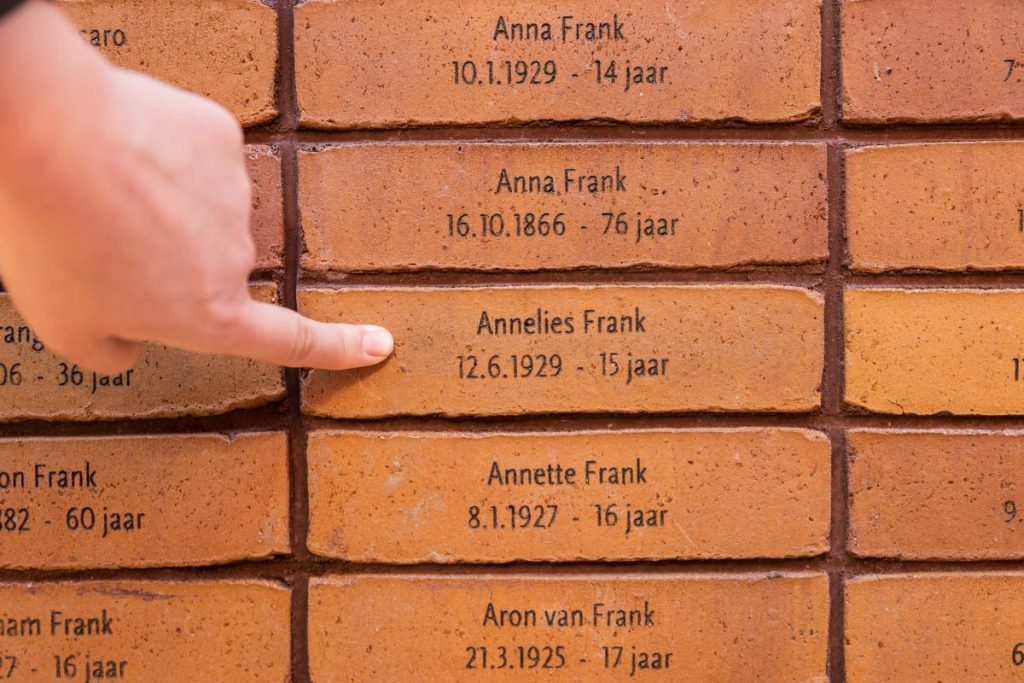 A woman pointing a brick with a name of someone who was killed during the Holocaust. 