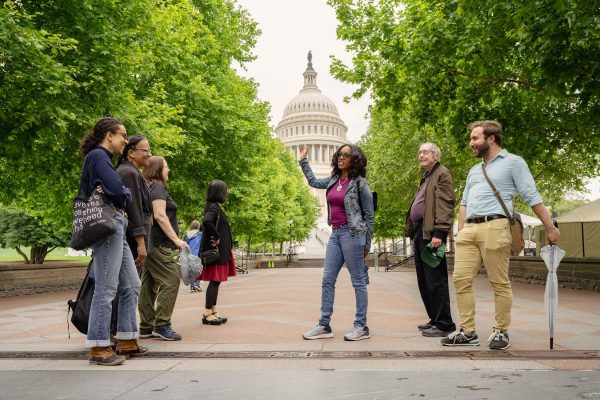 a group of people standing in front of a domed building in the far background