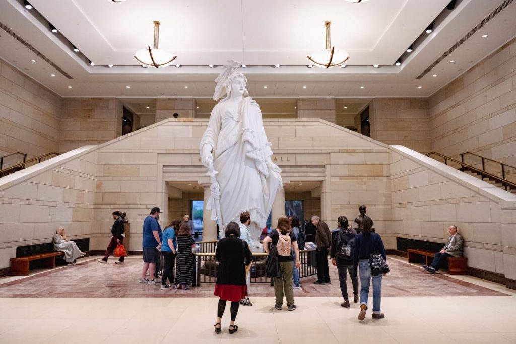 people standing in front of lobby with large statue