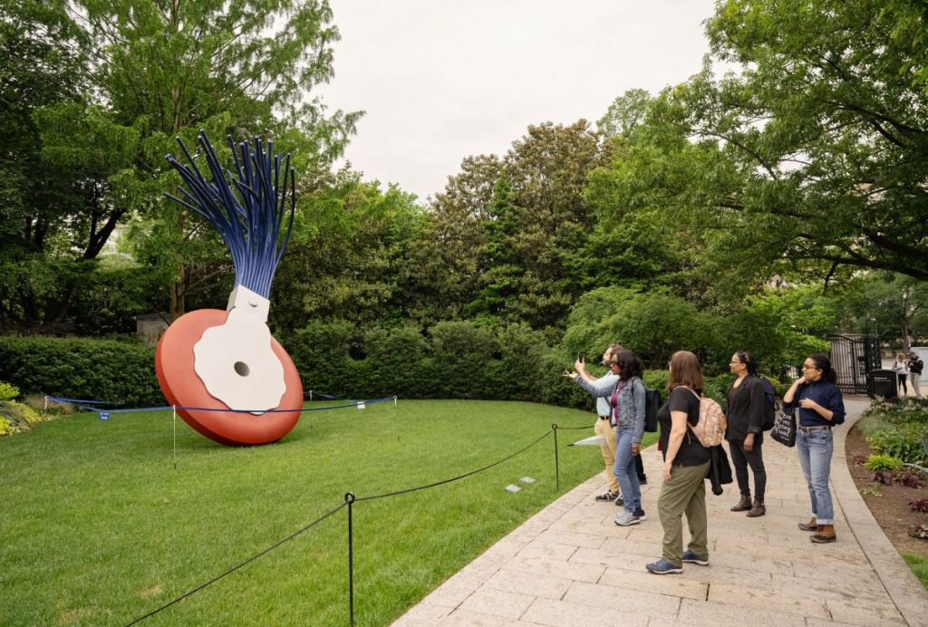 people looking at a large art piece on a green lawn