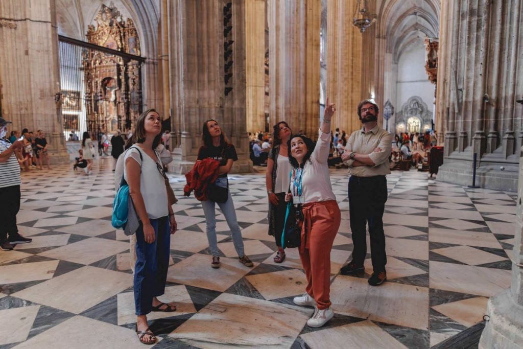 People inside the Seville cathedral looking at the ceiling. 