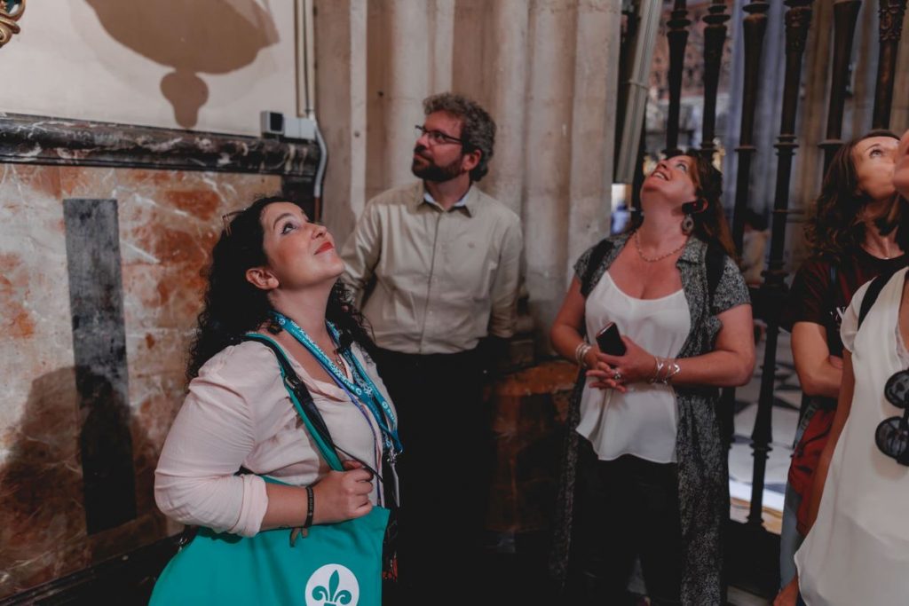 People looking up at the ceiling admiring the architecture and learning about Seville cathedral facts. 