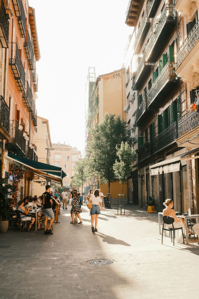 People sitting at an outdoor restaurant and others walking around Chueca in Madrid. 