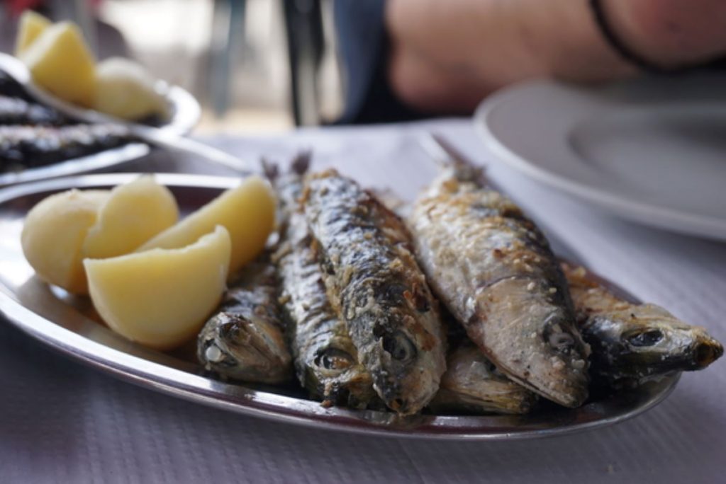 Sardines on a platter with fresh potatoes. 