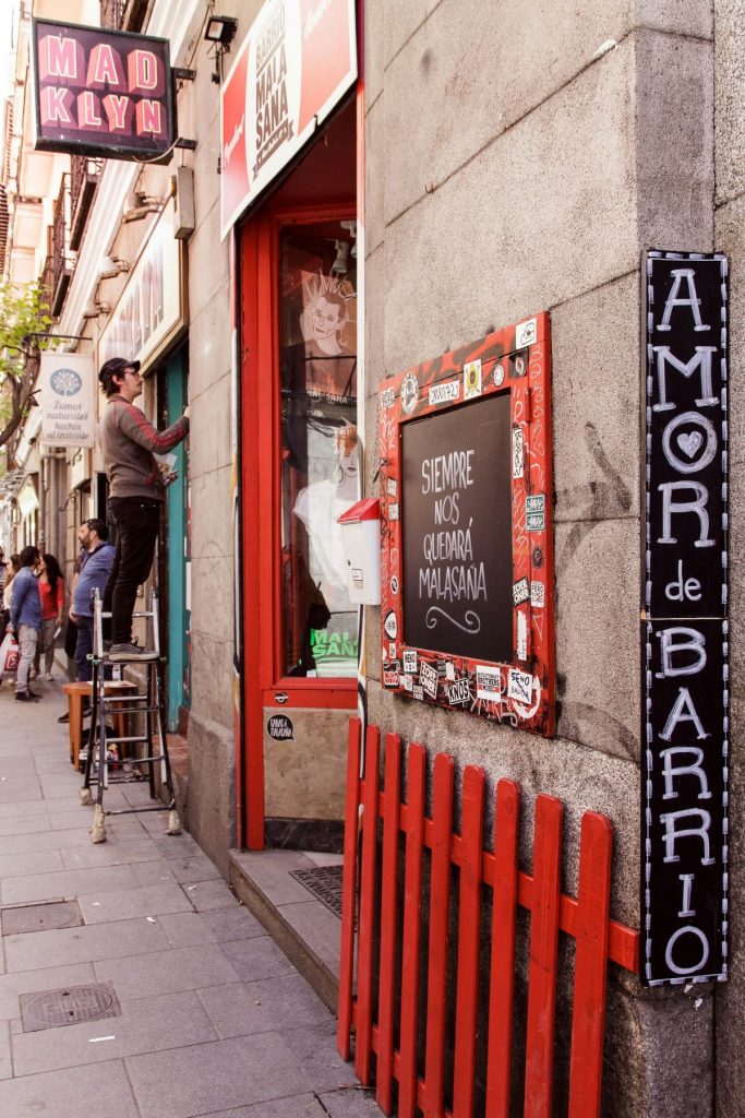 A person painting a storefront in Malasana, a barrio in Madrid. 