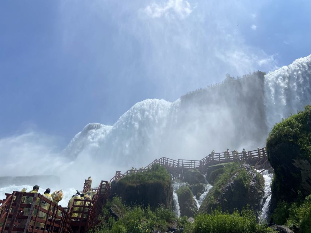 People walking on a bridge near waterfalls.